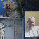 A bricklayer works on a wall next to a photograph of Pope Francis in Havana