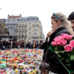 People observe a minute of silence at a street memorial to victims of Tuesdays’s bombings in Brussels, Belgium