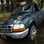 A damaged car is seen in flood waters in St. Amant