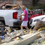 A woman walks through piles of debris in front of flood damaged homes in Prairieville
