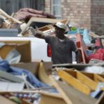 Billy Bethley throws flood damaged floor board on to a pile of debris in Prairieville