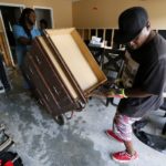 Micheal Andrews and his friend Clarence Robertson remove furniture out of his flood damaged home at the South Point subdivision in Denham Springs