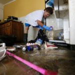 Samantha Labatut cleans out a refrigerator inside her flood damaged kitchen in St. Amant