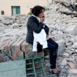 A woman sits along the road following a quake in Amatrice