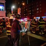 New York City police and firefighters stand near the site of an explosion in the Chelsea neighborhood of Manhattan, New York