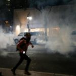 A man runs from tear gas in uptown Charlotte, NC during a protest of the police shooting of Keith Scott, in Charlotte