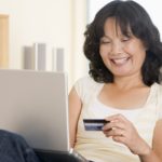 storyblocks/woman-in-living-room-using-laptop-holding-credit-card-and-smiling_SYpVG30Hj