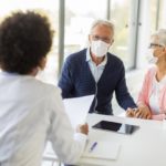 senior-couple-with-protective-facial-masks-receive-news-from-black-female-doctor-office_52137-35215