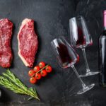 organic-picanha-steaks-near-bottle-glass-red-wine-black-textured-table-top-view_249006-8049