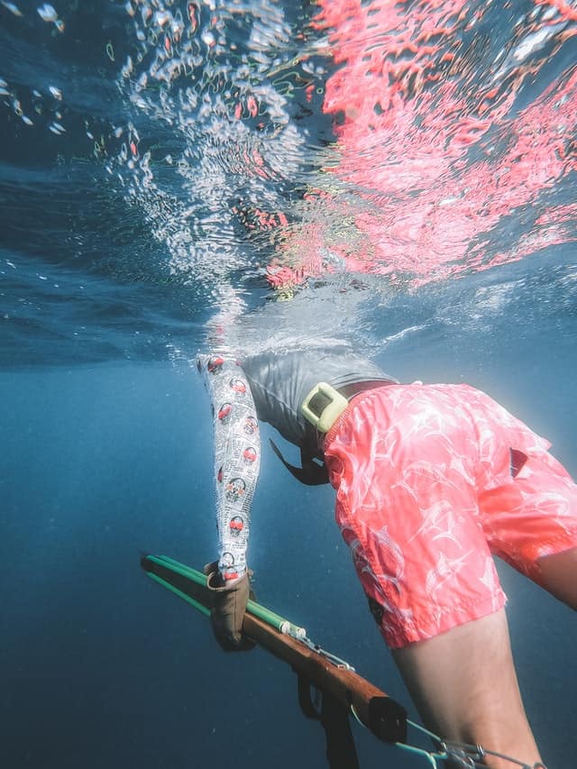 https://www.pexels.com/photo/person-diving-and-fishing-9881341/