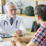 elderly-doctor-listening-young-patient