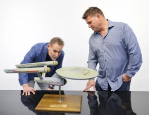 Heritage’s executive vice president, Joe Maddalena and Eugene “Rod” Roddenberry, look at the USS Enterprise model.